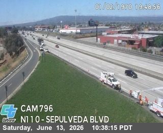Road crew and vehicles present on the shoulder of the highway.