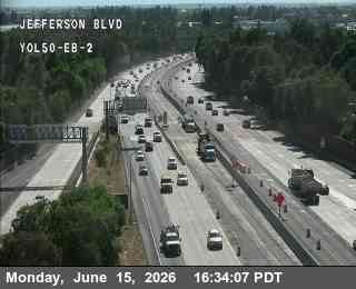 Construction vehicles and cones on the right shoulder of the highway.