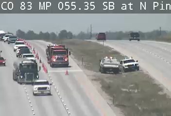 Fire truck and police cars on the side of the road with cones.