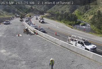 Construction zone with workers and equipment, traffic cones, and a utility truck.