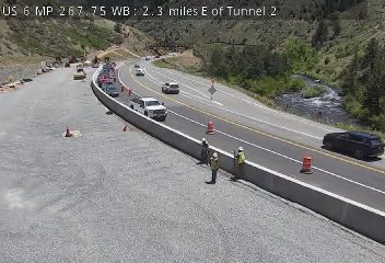 Construction workers and cones on the side of the highway, traffic is moving.