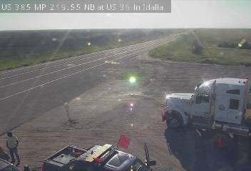 A truck and a person in a safety vest are on the side of the road.