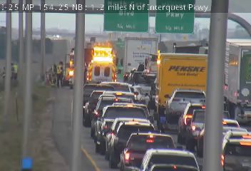 Ambulance with flashing lights and emergency personnel on the left shoulder