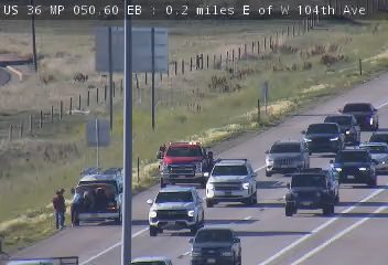 Tow truck and person attending to a vehicle on the shoulder of the highway.