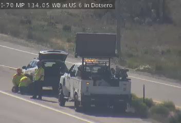 Emergency responders assisting a vehicle on the side of the highway.