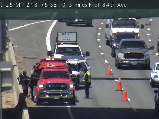 Emergency responders and vehicles on the side of the highway with traffic cones.