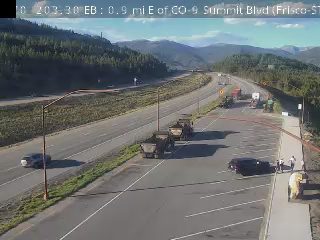 Multiple trucks and people appear to be working on the side of the road.