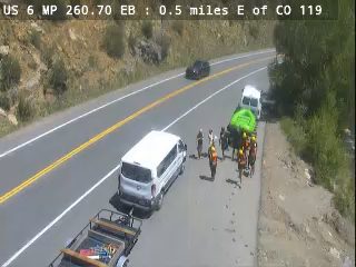 Multiple people and vehicles gathered on the shoulder of the road.