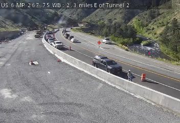 Construction vehicles and personnel are present on the roadway.