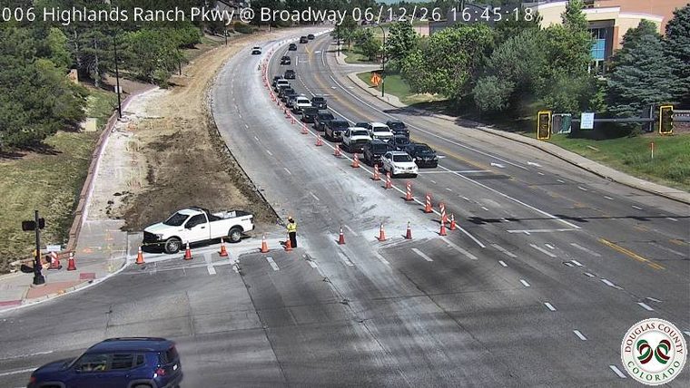 Construction zone with a worker and traffic cones, traffic is backed up.