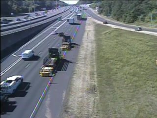 Emergency responders and vehicles are present on the shoulder of the highway.