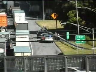 Police car and officers on the highway near an exit ramp.
