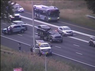 Tow truck and police car on the highway with a person standing nearby.