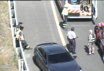 Emergency responders and vehicles are present at a roadside incident.