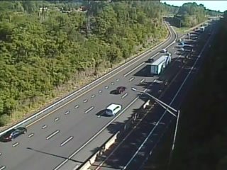Emergency responders and vehicles are present on the highway shoulder, causing traffic backup.