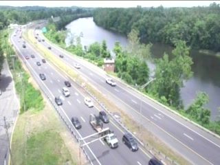 Emergency vehicle and personnel on the highway shoulder with cones.