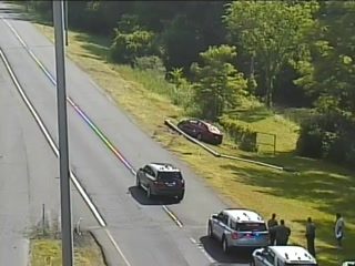 Police and other vehicles on the roadside with people present.