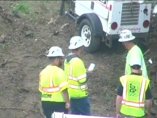 Workers in safety vests and hard hats gathered near a utility vehicle.