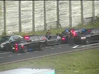 Multiple police cars with red and blue lights on the roadway