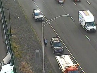 Police and tow truck on scene with people beside vehicles on the highway.