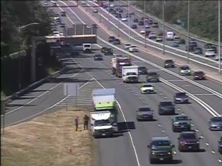 Two people and a white truck are on the shoulder of the highway.