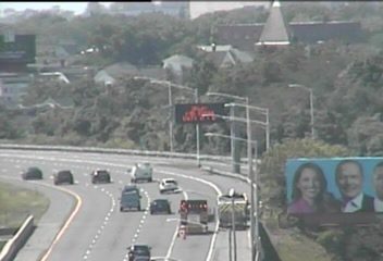 Fire truck and emergency vehicle on the side of the highway with cones.