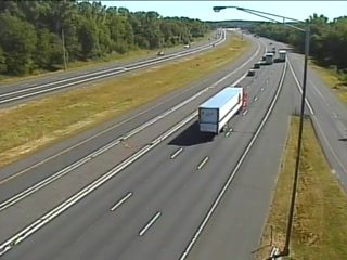 A trailer truck is stopped, with cones and what appears to be a responder vehicle behind it.