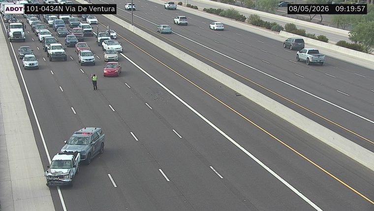 Police SUV with red and blue lights on next to a damaged pickup truck in the left lane