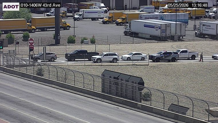 Police vehicle and a pedestrian on the frontage road next to a white pickup truck