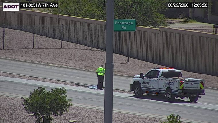 ADOT Incident Response Unit truck with flashing lights and a worker in a high-visibility vest on the right shoulder
