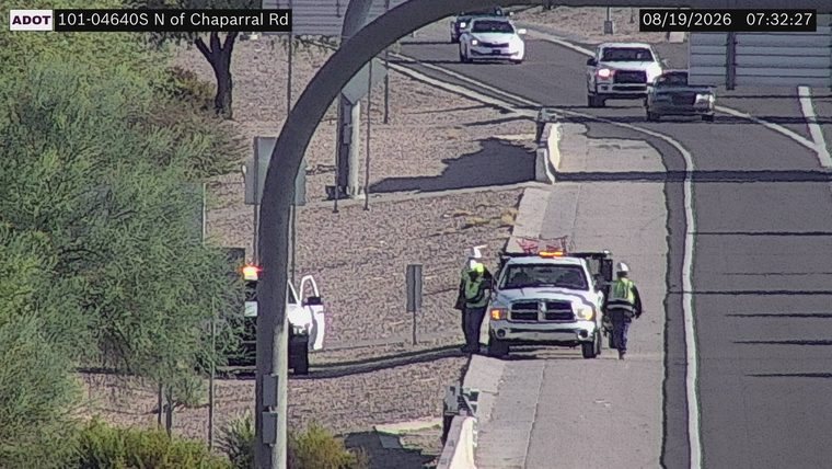Tow truck with hazard lights on and two workers on the right shoulder