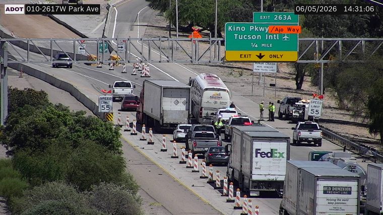 Multiple police vehicles and workers responding to a crash involving a bus and a semi-truck in the left lanes
