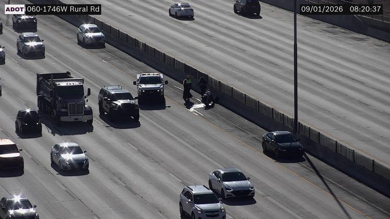 Two individuals and a motorcycle in the right lane with a spill on the roadway