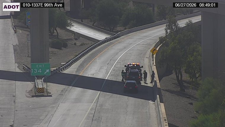 Tow truck with hazard lights on and several people around a vehicle on the right shoulder