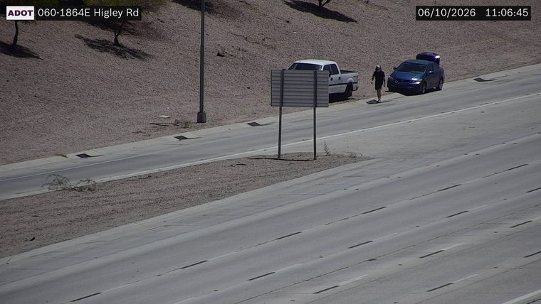 Person walking near a blue sedan on the right shoulder