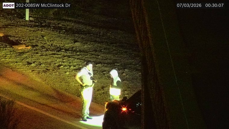 Police officer and another person standing next to a vehicle on the right shoulder