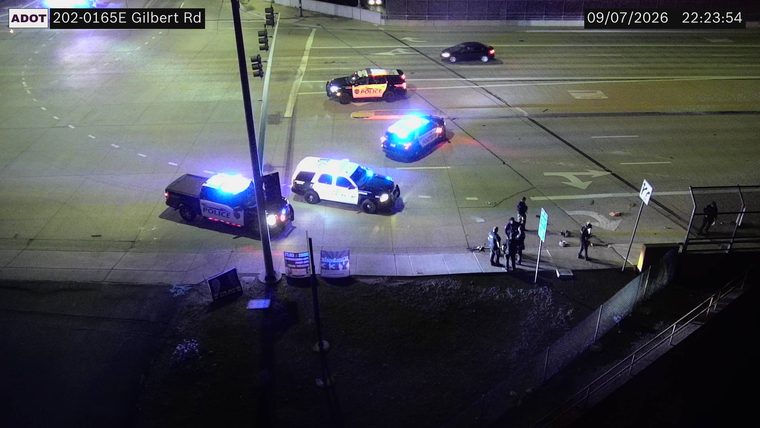 Multiple police cars with lights on and several individuals on the roadway