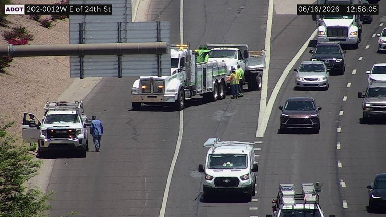 Two workers and a tow truck assisting a dump truck in the right lane