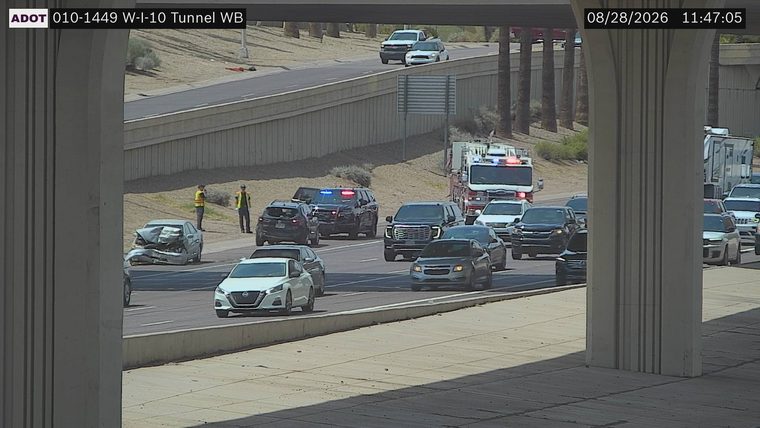 Severely damaged sedan in the left lane, with a police SUV and fire truck with lights on nearby