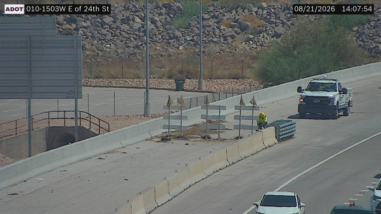 Worker in high-visibility vest and hard hat near construction barriers