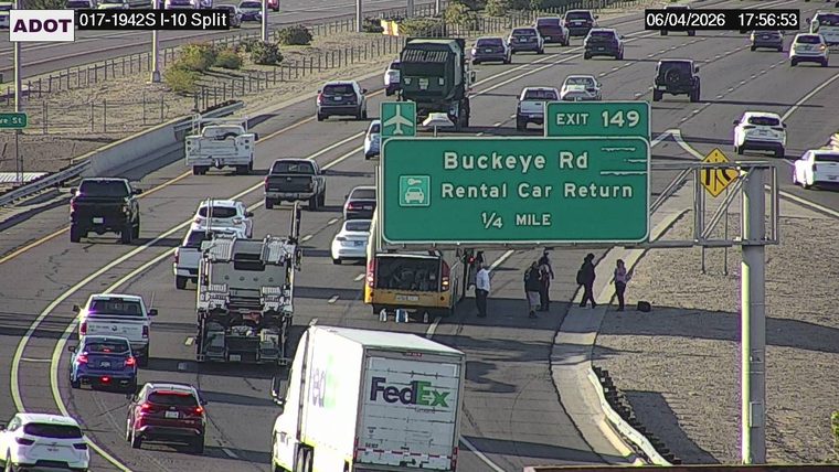 Several people standing on the shoulder near a yellow vehicle