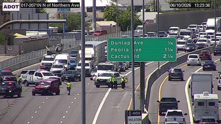 Red jeep with visible damage in the left lane, with two individuals in high-visibility vests standing nearby
