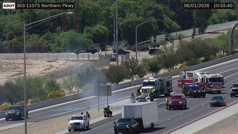 Fire truck and emergency personnel attending to a vehicle with smoke in the right lane