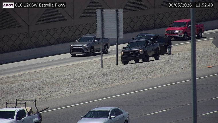 Person standing next to a black pickup truck on the right shoulder
