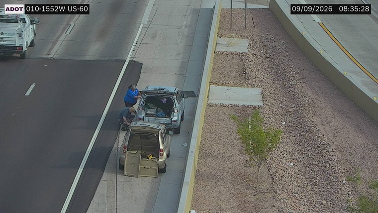 Two people attending to two vehicles on the right shoulder