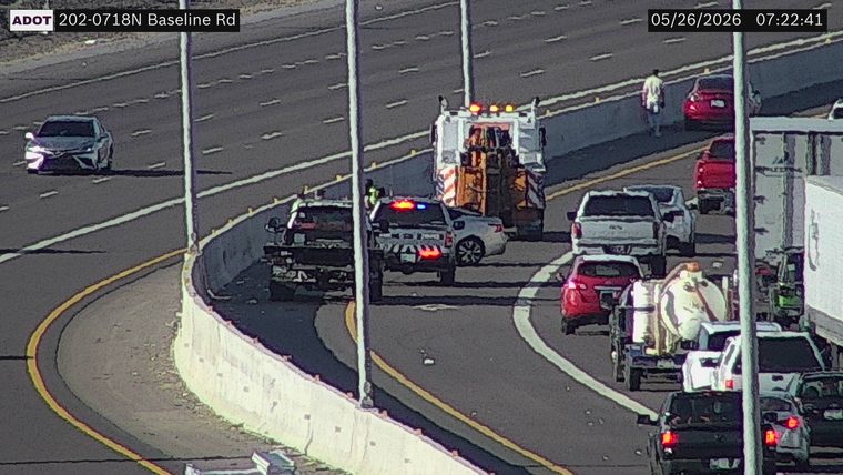 Police vehicle with flashing lights and a highway service truck on the left shoulder assisting a stopped vehicle