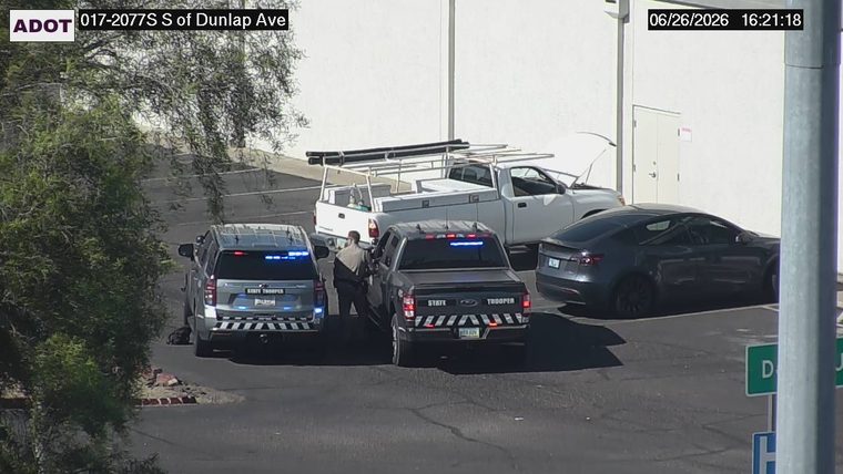 Two state trooper vehicles and a civilian interacting in a parking lot