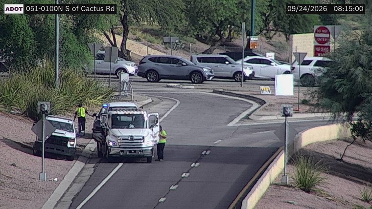 Tow truck and two workers on the shoulder near a white vehicle
