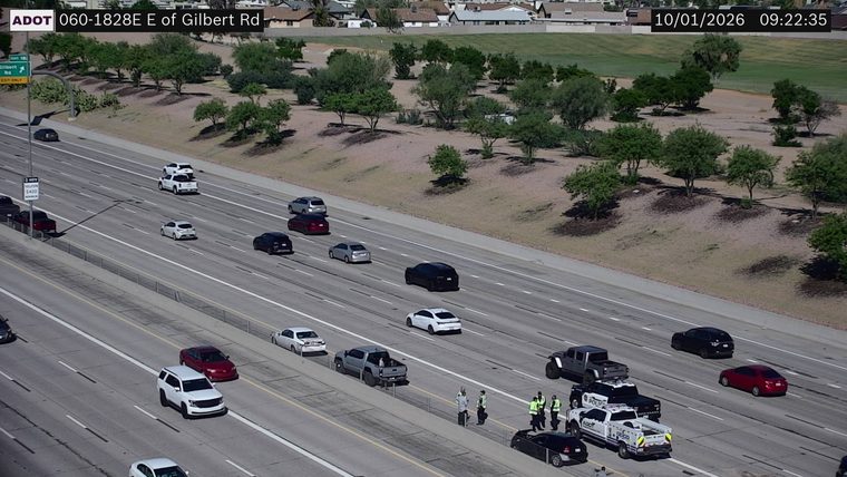 Three police vehicles and two individuals on the right shoulder