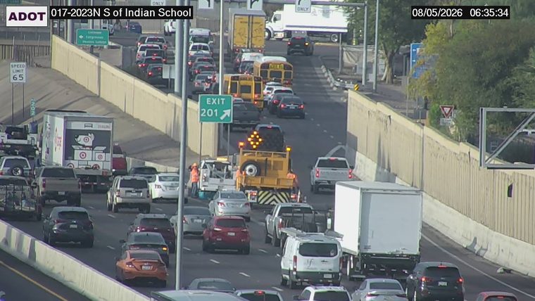 Construction vehicle with flashing arrow board and workers in the left lane